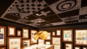 Un interior moderno con vitrinas de madera, un mueble central de madera y diseños geométricos en el techo.