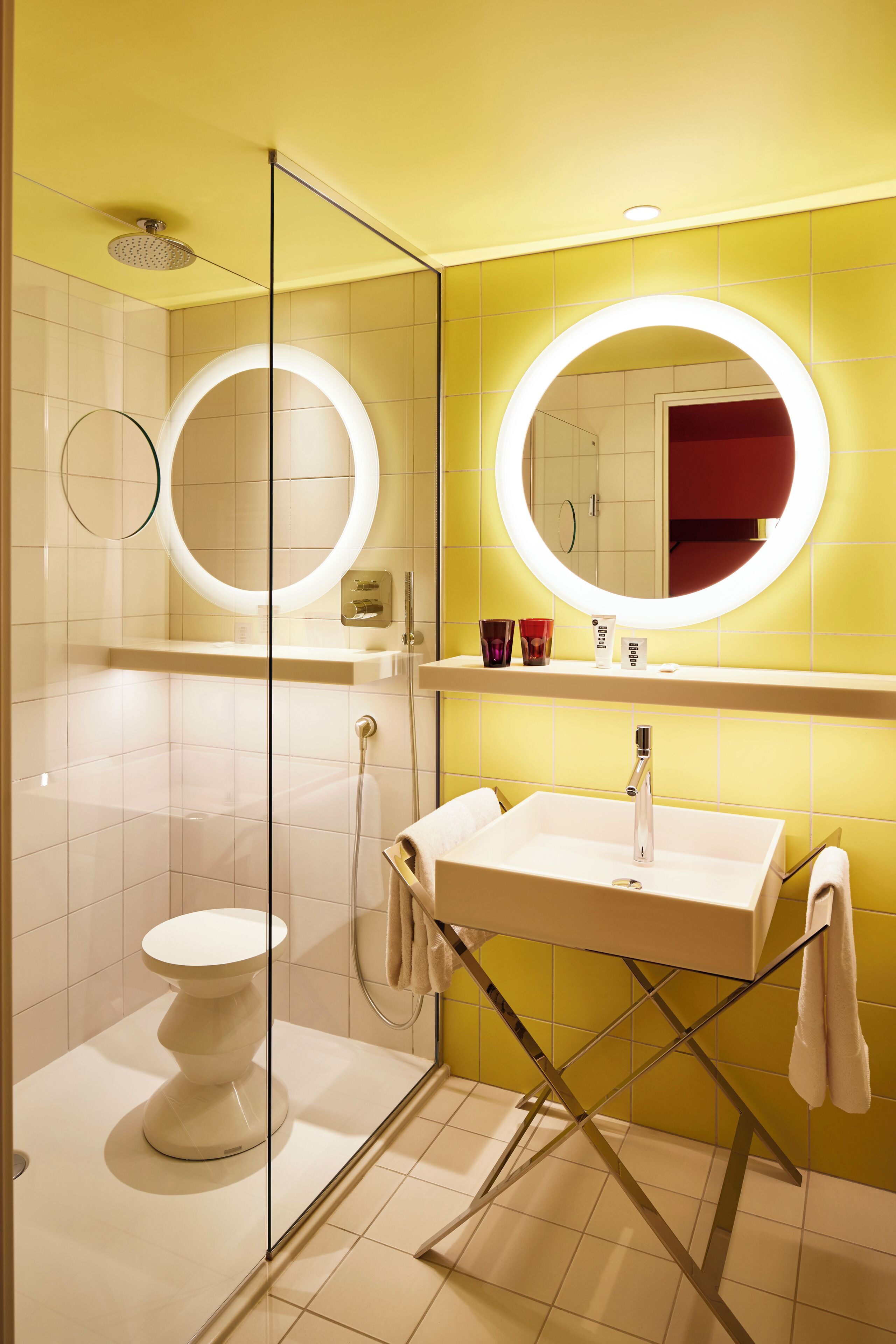 A modern bathroom with a glass-enclosed shower, a white sink, and a large mirror with illuminated edges.
