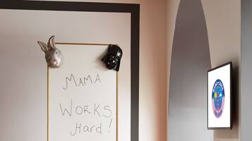 Una sala de conferencias con una pizarra mostrando 'MAMA WORKS Hard!' y un logotipo enmarcado en la pared.