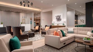 A modern living room with a sectional sofa, armchairs, and a coffee table. There is a bookshelf and a dining area in the background. - Residence Inn by Marriott Bend (Bend)