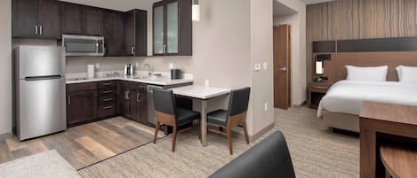 Una habitación de hotel moderna con kitchenette, una cama, un escritorio y una zona de estar.