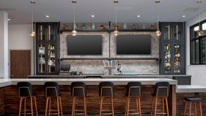 A modern kitchen with a bar area, built-in appliances, and a large TV. - Residence Inn by Marriott Bend (Bend)