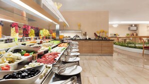 Un bufé con diferentes opciones de comida y una cocina moderna al fondo.