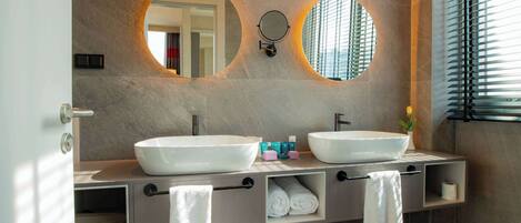 A modern bathroom with two large sinks, a mirror, and a towel rack.