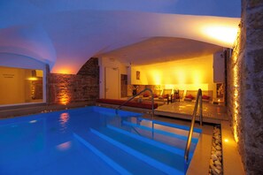 A swimming pool with steps leading into it, a stone wall, and a seating area with a lamp. - Boscolo Lyon Hôtel & Spa (Lyon)