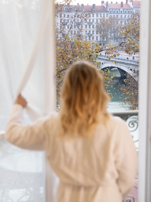 A person standing by a window with a view of a bridge and buildings.