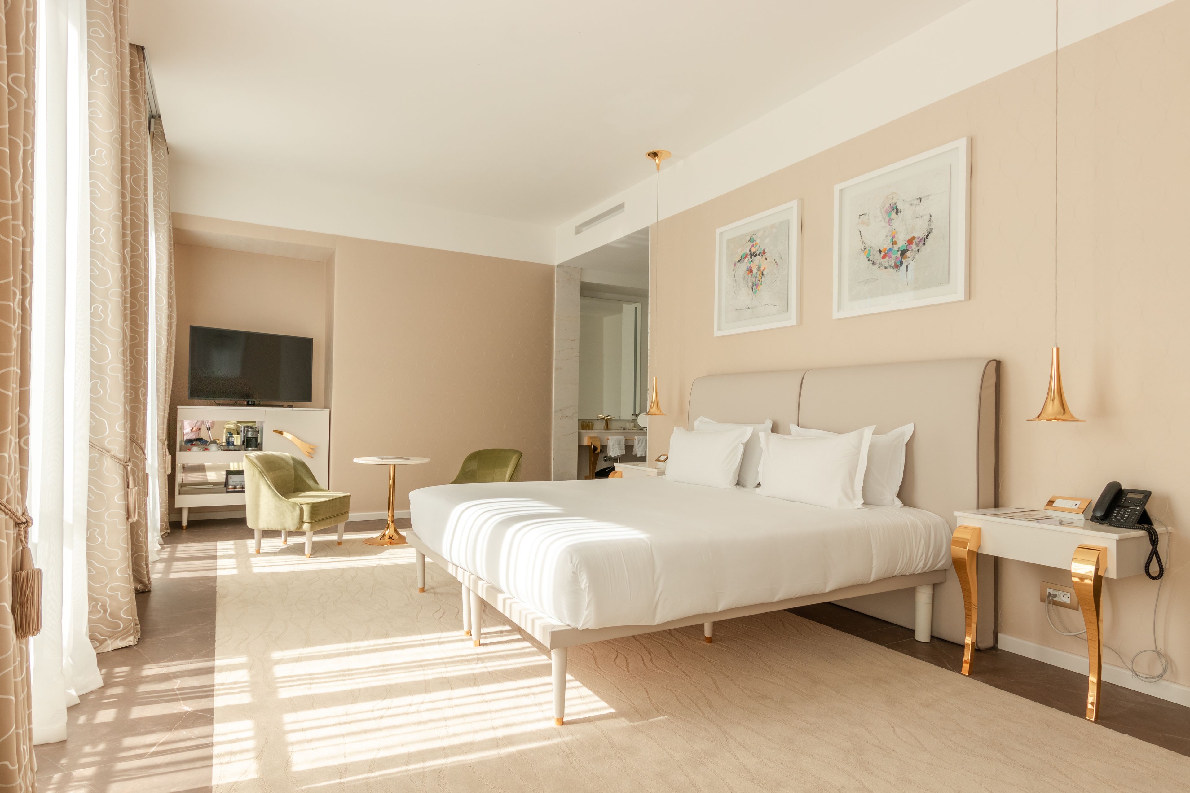 Een hotelkamer met een groot bed, een bureau, een stoel, een televisie en kunst aan de muren.