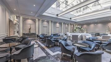 A spacious lobby with marble flooring, modern seating, and a high ceiling with skylights.