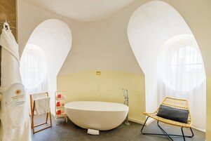 Un bagno moderno con una vasca freestanding, una sedia in vimini con cuscino e un portasciugamani.