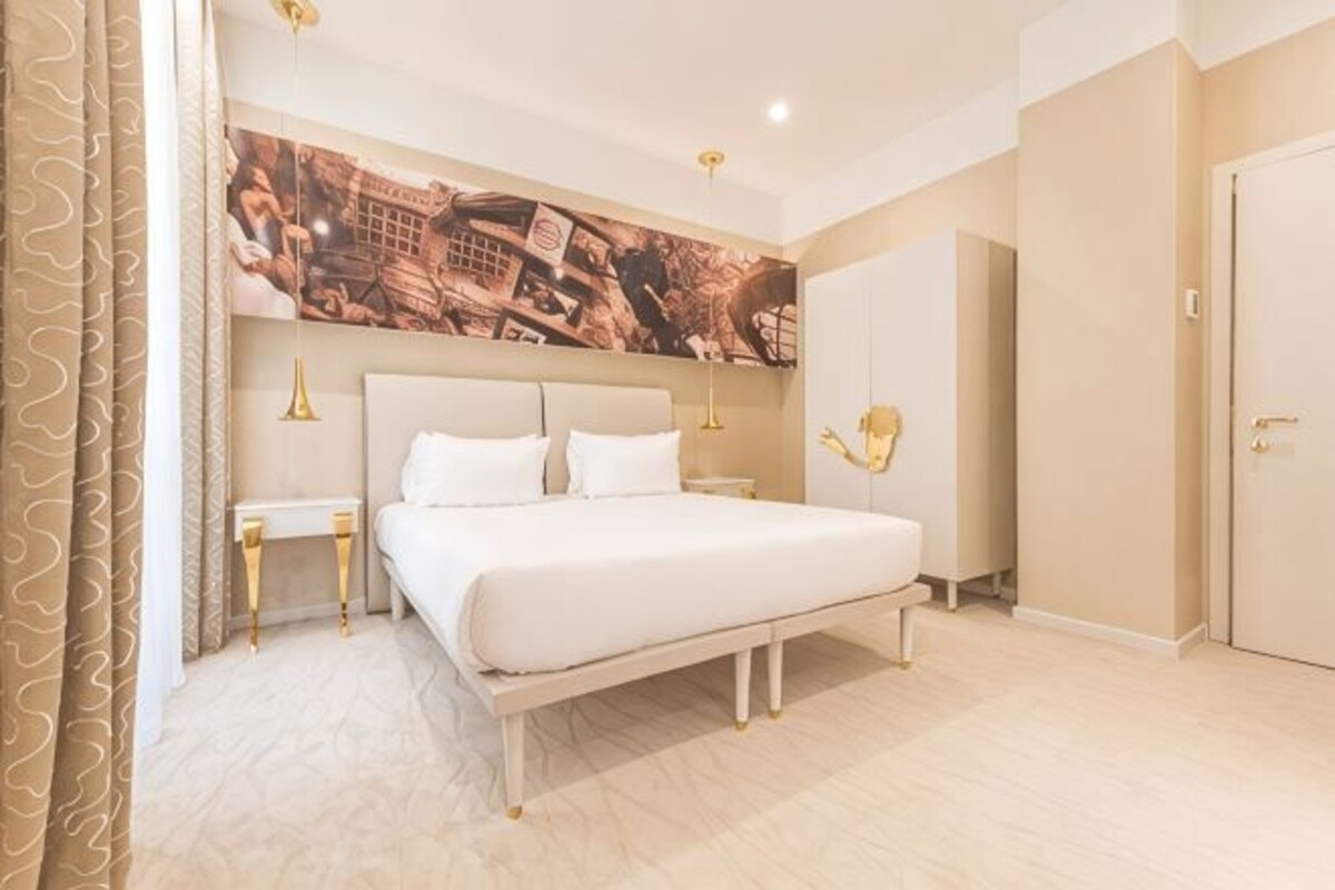 Um quarto com uma cama grande, duas mesas de cabeceira, uma obra de arte na parede e uma porta.