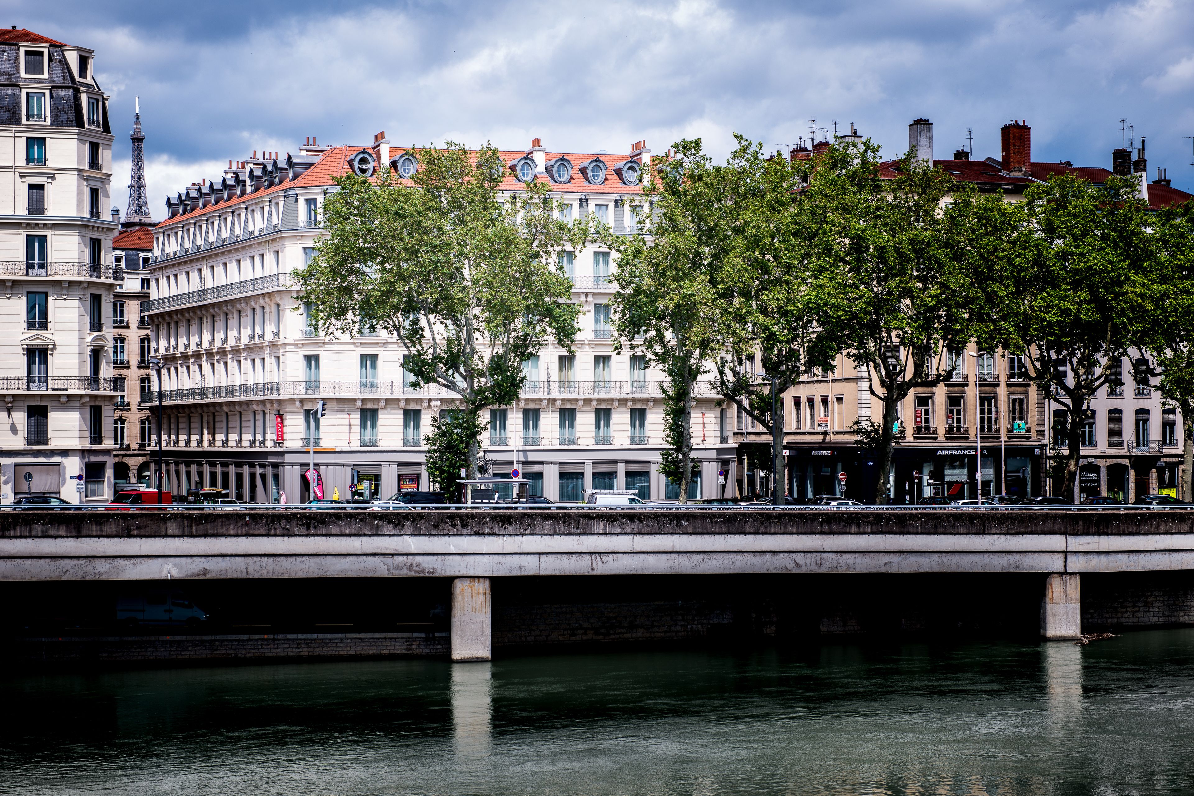 A bridge over a river with buildings on either side, including a prominent white building with a red roof.
