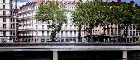 Un puente sobre un río flanqueado por edificios, entre ellos un edificio blanco destacado con techo rojo.