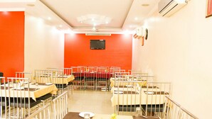 Comedor con mesas dispuestas para el servicio, un televisor montado en la pared y un equipo de aire acondicionado.