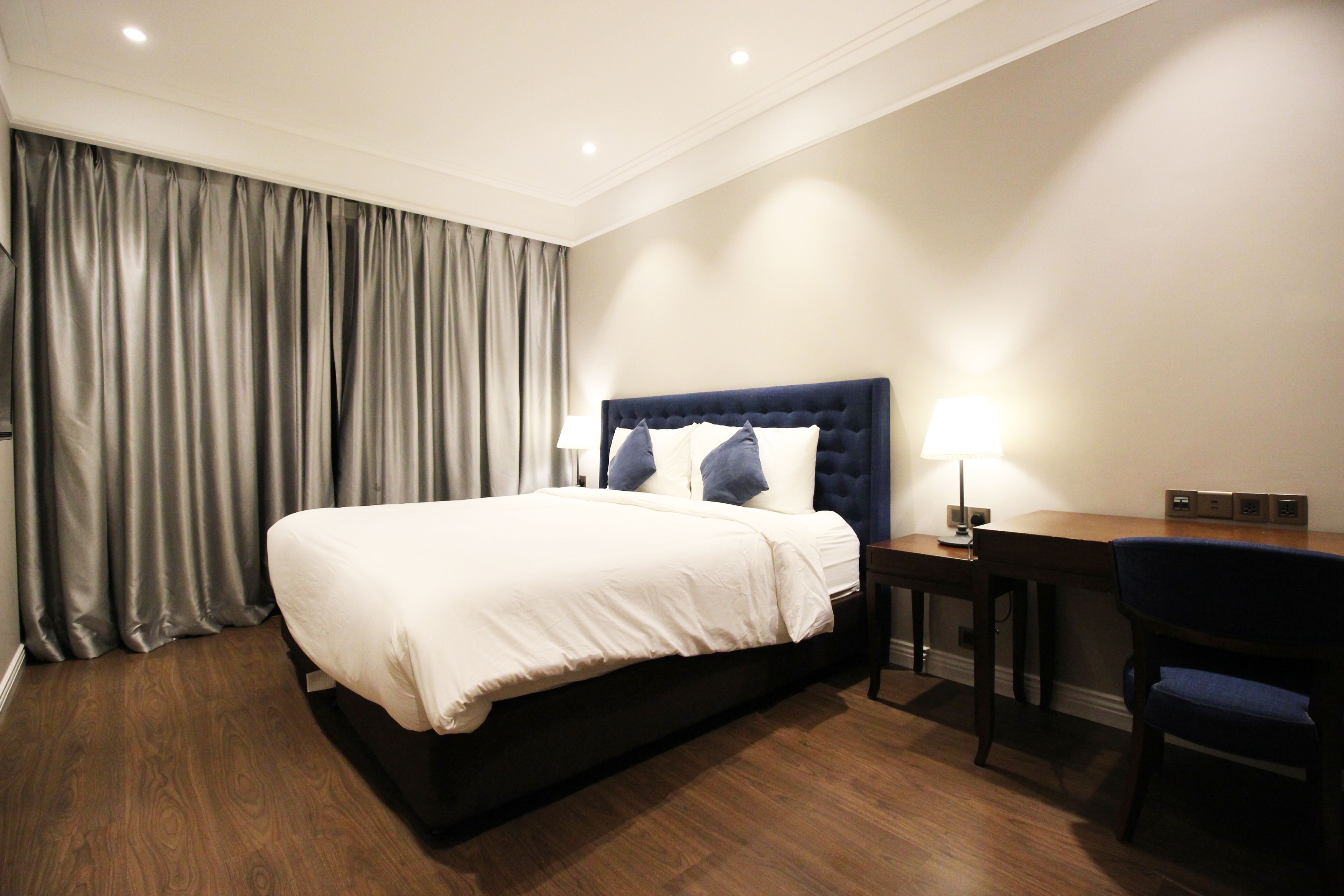 Una habitación de hotel con una cama grande, un escritorio, una silla y una lámpara.