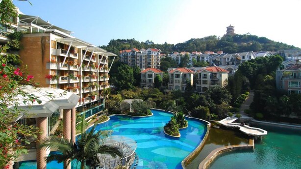 A hotel with multiple floors, a swimming pool with a fountain, and a pagoda in the background. - Guangzhou Yihe Hotel (Guangzhou)