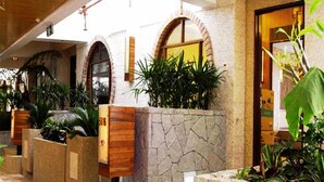 A lobby with stone walls, wooden planters with greenery, and a reception desk. - Guangzhou Yihe Hotel (Guangzhou)