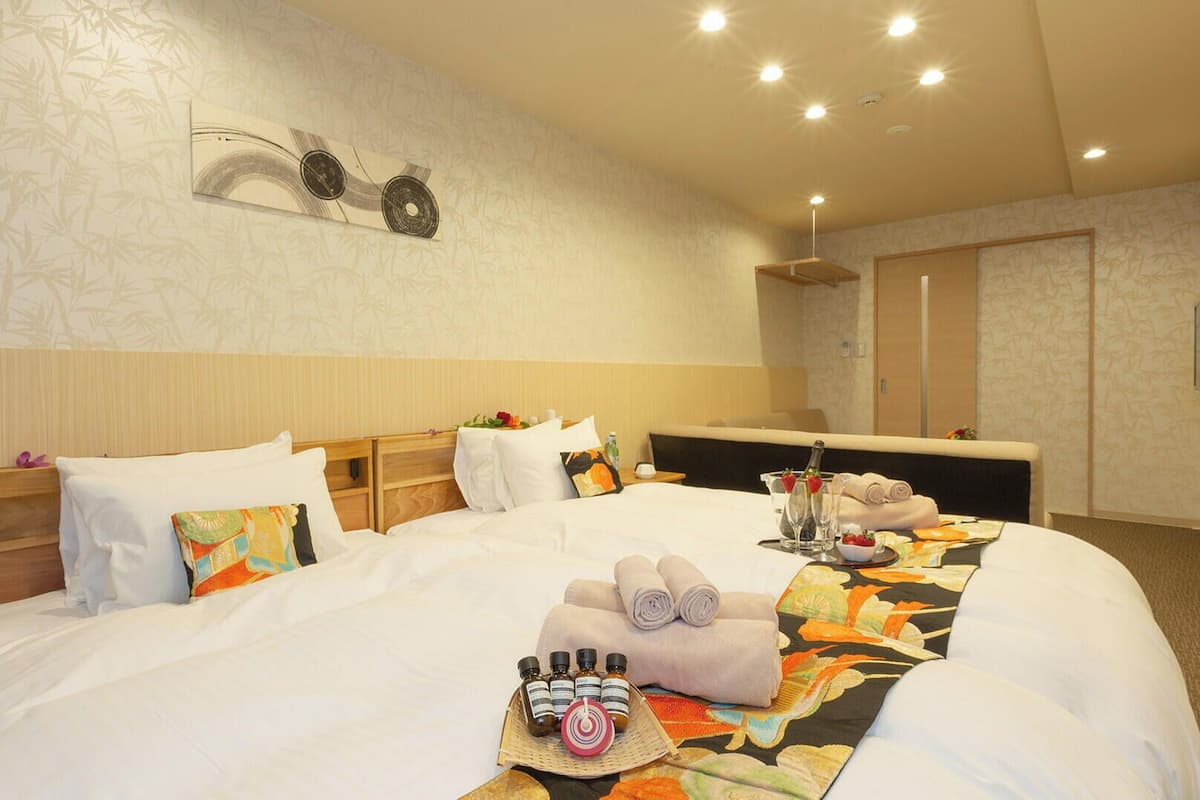 A hotel room with a bed, bedside tables, a headboard, a TV, and a bathroom with a shower and toilet.