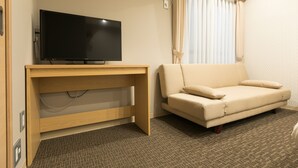 A hotel room with a flat-screen TV on a wooden desk, a beige sofa, and a patterned carpet. - Stay SAKURA Kyoto Gyoen East (Kyoto)