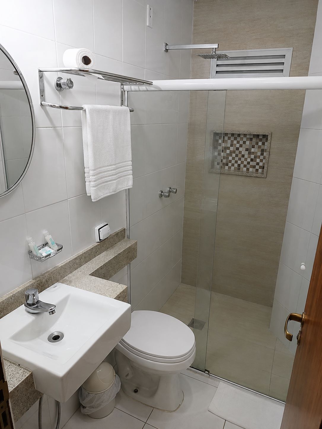 Un baño moderno con ducha de vidrio, inodoro, lavamanos y espejo.