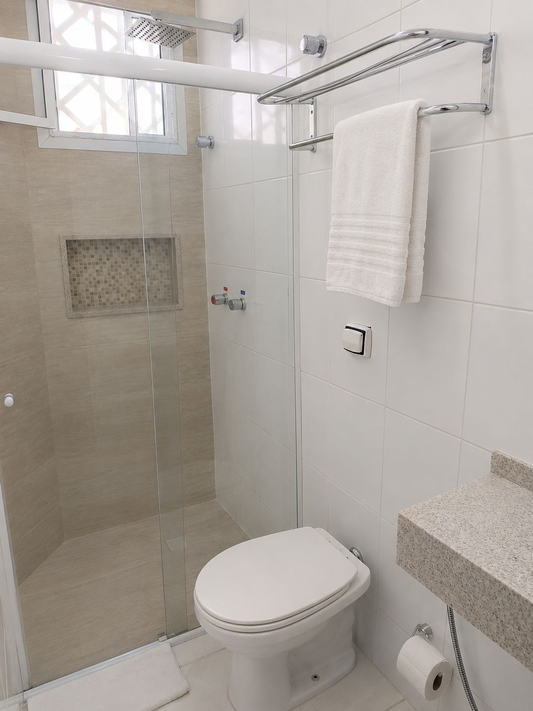 Un baño moderno con ducha de vidrio, inodoro blanco y toallero.