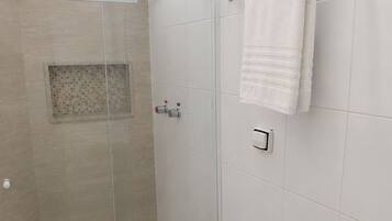 Un baño moderno con ducha de vidrio, inodoro blanco y toallero.