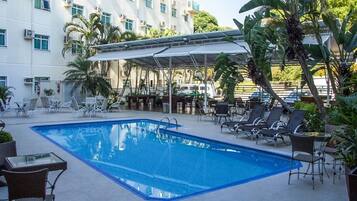 Una piscina al aire libre, sillones reclinables de piscina