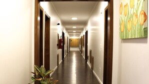 A hotel hallway with wooden floors, white walls, and a painting of tulips on the right. - Hotel Serra de Jundiaí (Jundiai)