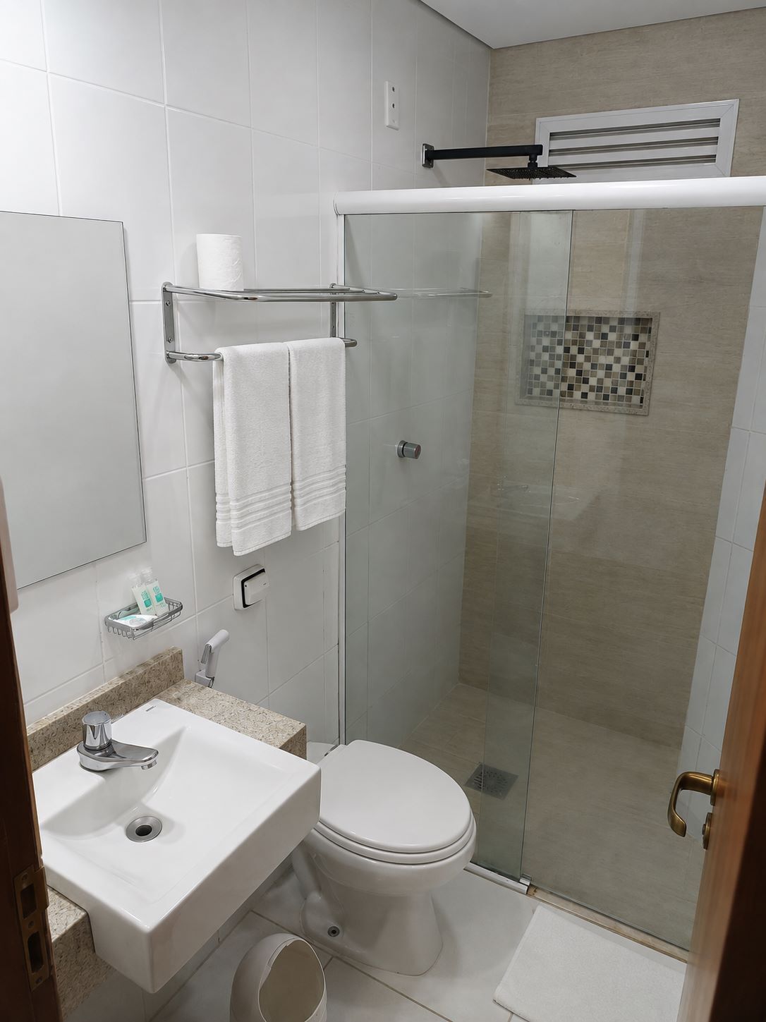 A modern bathroom with a glass-enclosed shower, a white sink, and a toilet.