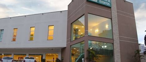 Un edificio con un cartel que dice "Serra Jundiai Centro de Eventos" y un estacionamiento con coches.