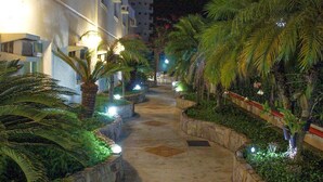 A pathway flanked by palm trees and illuminated by soft lights, leading to a building with multiple windows. - Hotel Serra de Jundiaí (Jundiai)