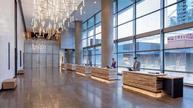 A spacious lobby with a modern design, featuring a reception desk, large windows, and a high ceiling with hanging lights. - Hyatt Regency Seattle (Seattle)
