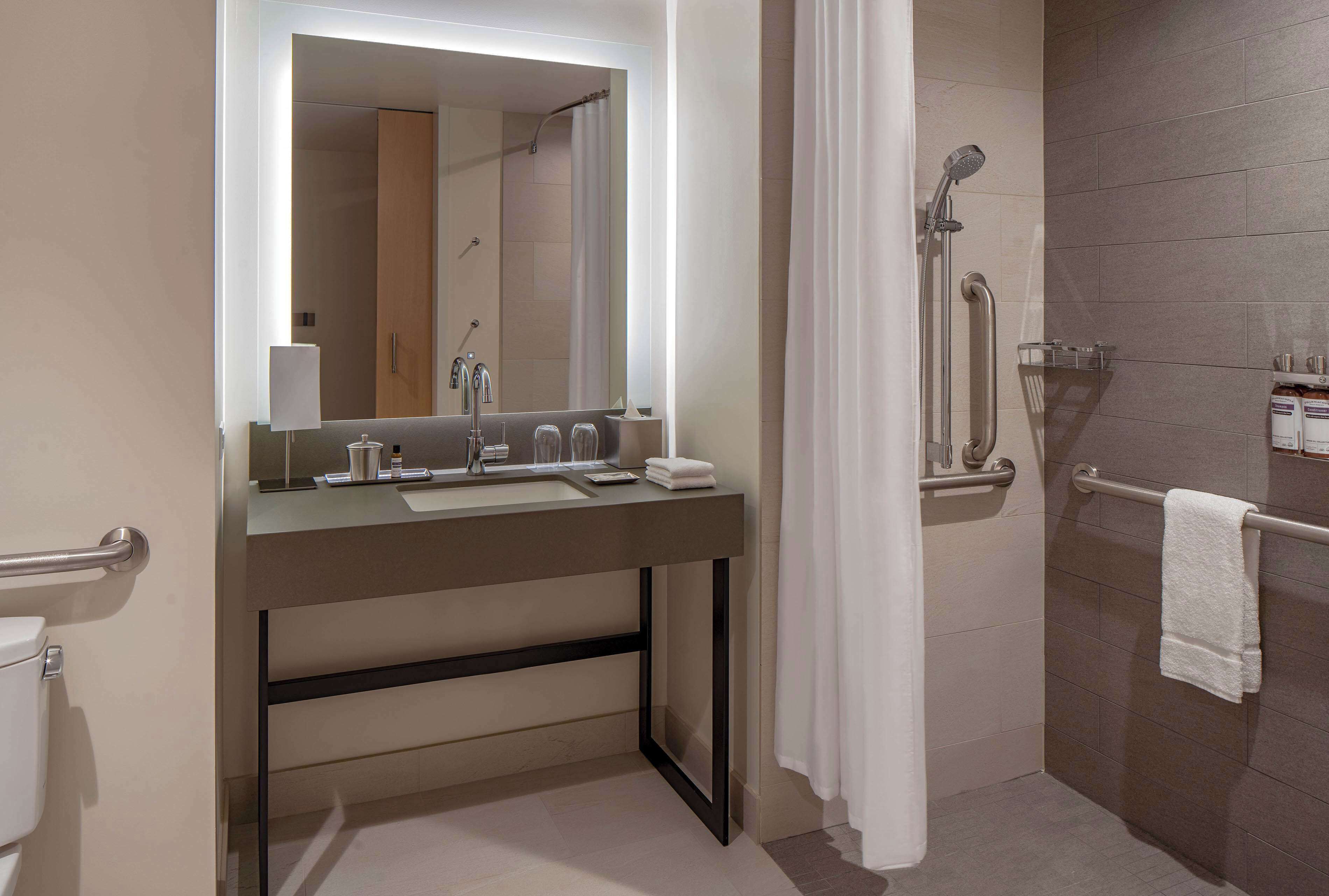 Un baño moderno con lavamanos, espejo y zona de ducha.