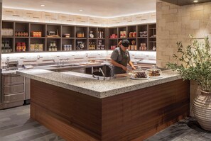 A modern kitchen with a central island, stainless steel appliances, and neatly organized shelves with kitchenware and spices.