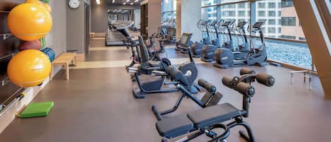 A modern gym with various exercise equipment, including treadmills, elliptical machines, and weight stations.