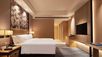 A hotel room with a large bed, bedside tables, a flat-screen TV, and a wall-mounted artwork.