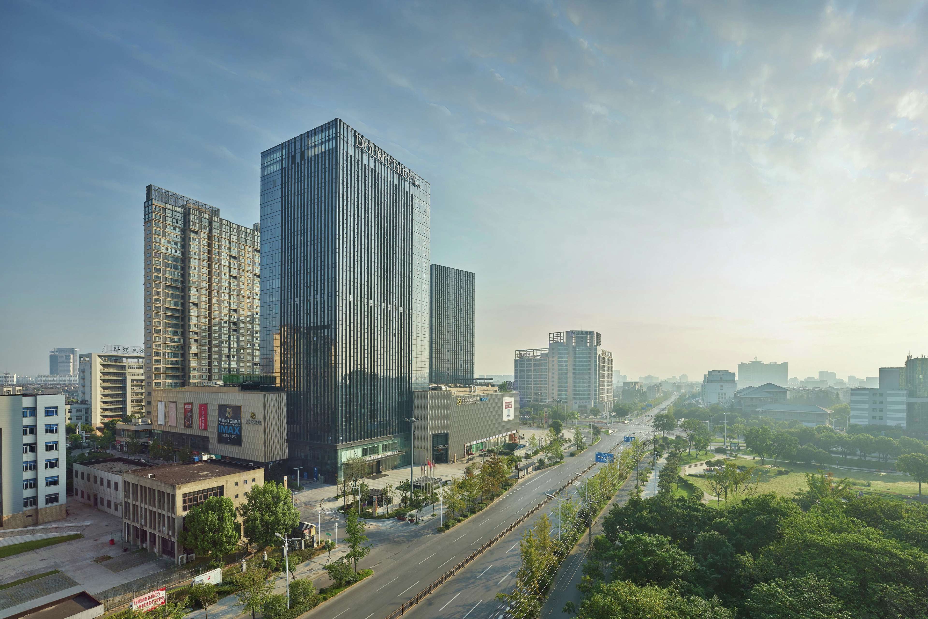 A modern urban landscape with high-rise buildings, a wide road, and green spaces.