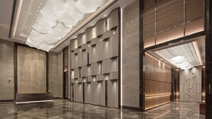 A modern hotel lobby with a polished marble floor, a reception desk, and a large wall with a unique geometric pattern. - Doubletree by Hilton Yangzhou (Yangzhou)
