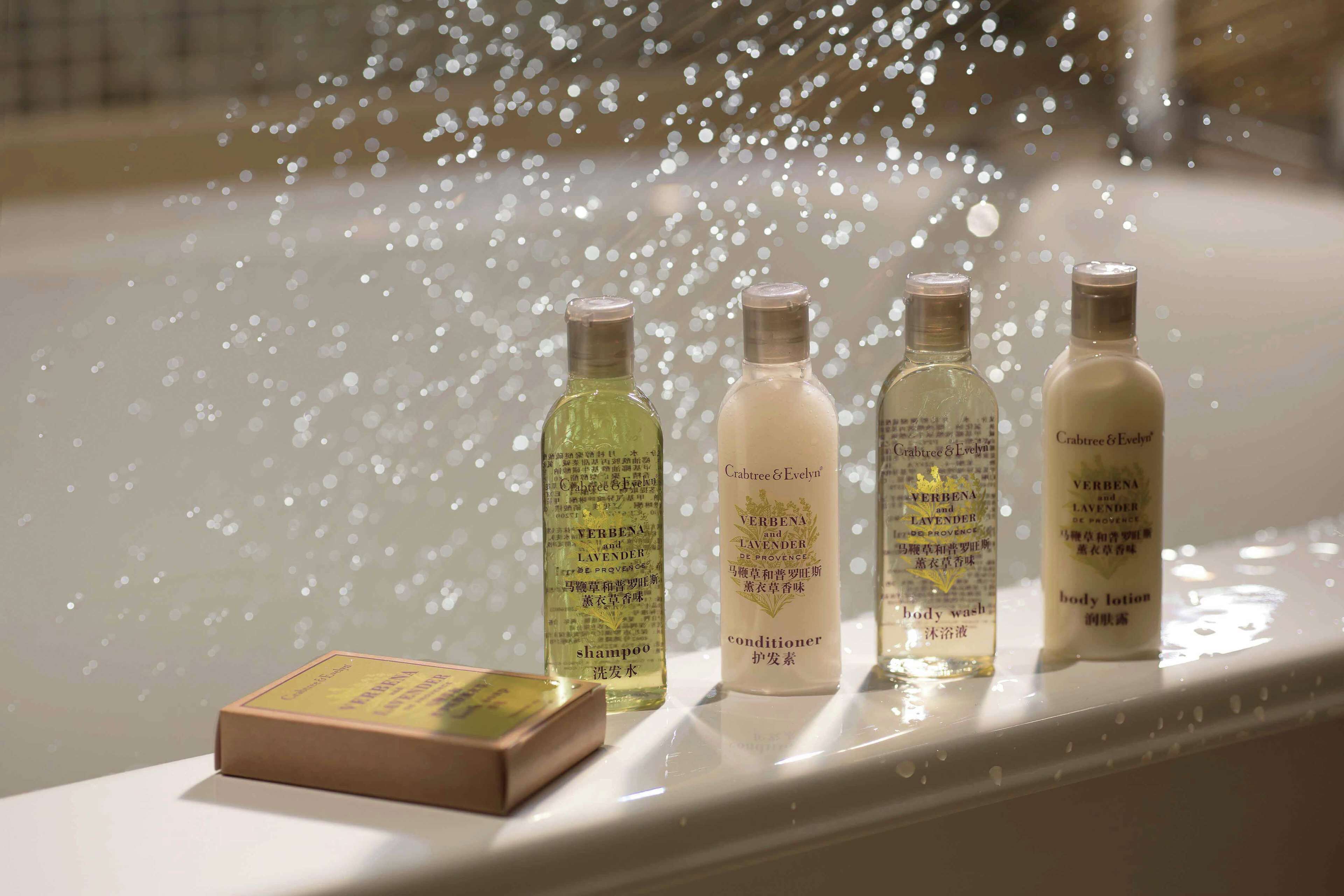 A bathtub with four bottles of Crabtree & Evelyn body wash and conditioner, and a box of shampoo.