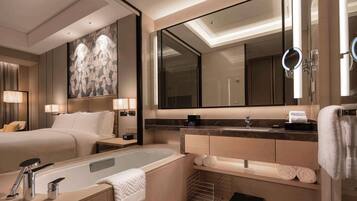 Un baño de hotel moderno con una bañera grande, un tocador con espejo y un espejo grande sobre el lavabo.
