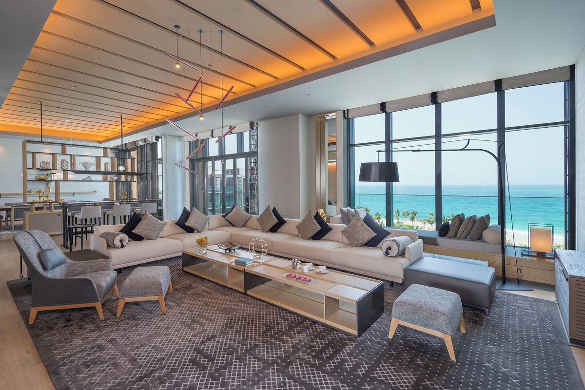 A modern living room with a large sectional sofa, a coffee table, and a view of the ocean.