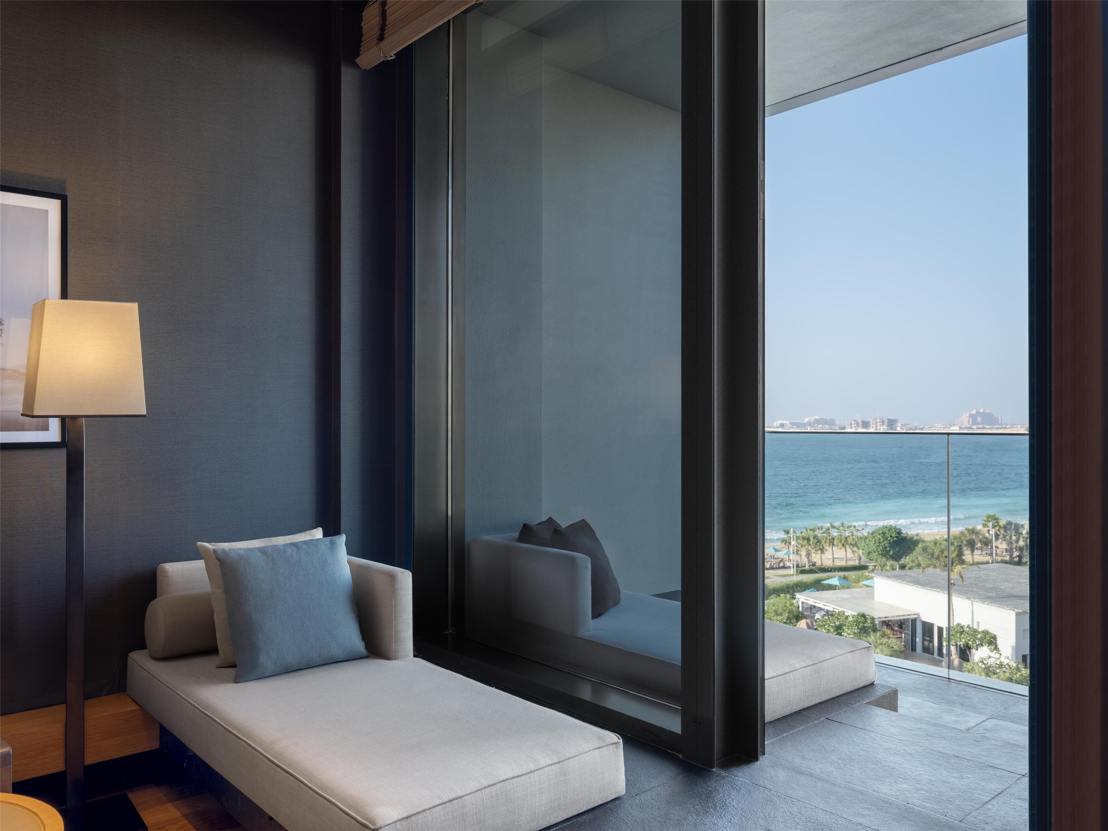 A modern hotel room with a balcony, a sofa, and a lamp.