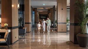 Eine moderne Hotelhalle mit glänzendem Holzboden, einer Rezeption und einer großen Pflanze in einem Topf.