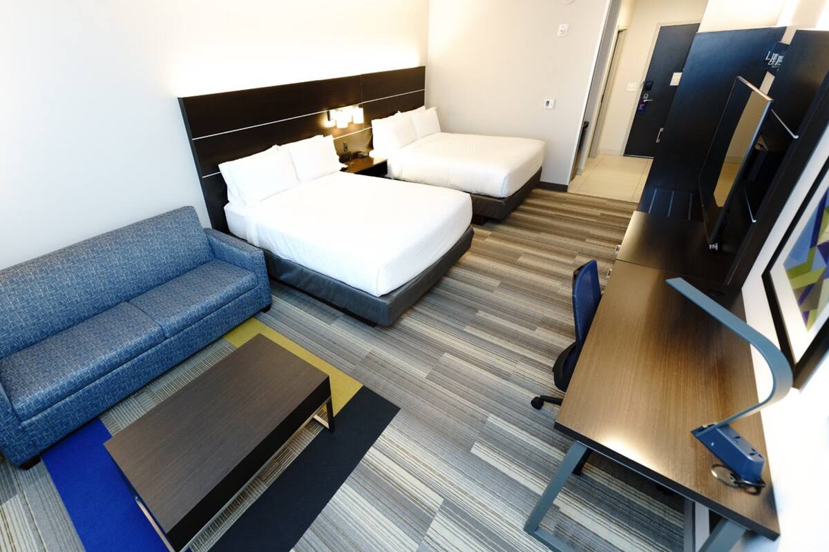 A hotel room with a bed, a sofa, a desk, and a TV.