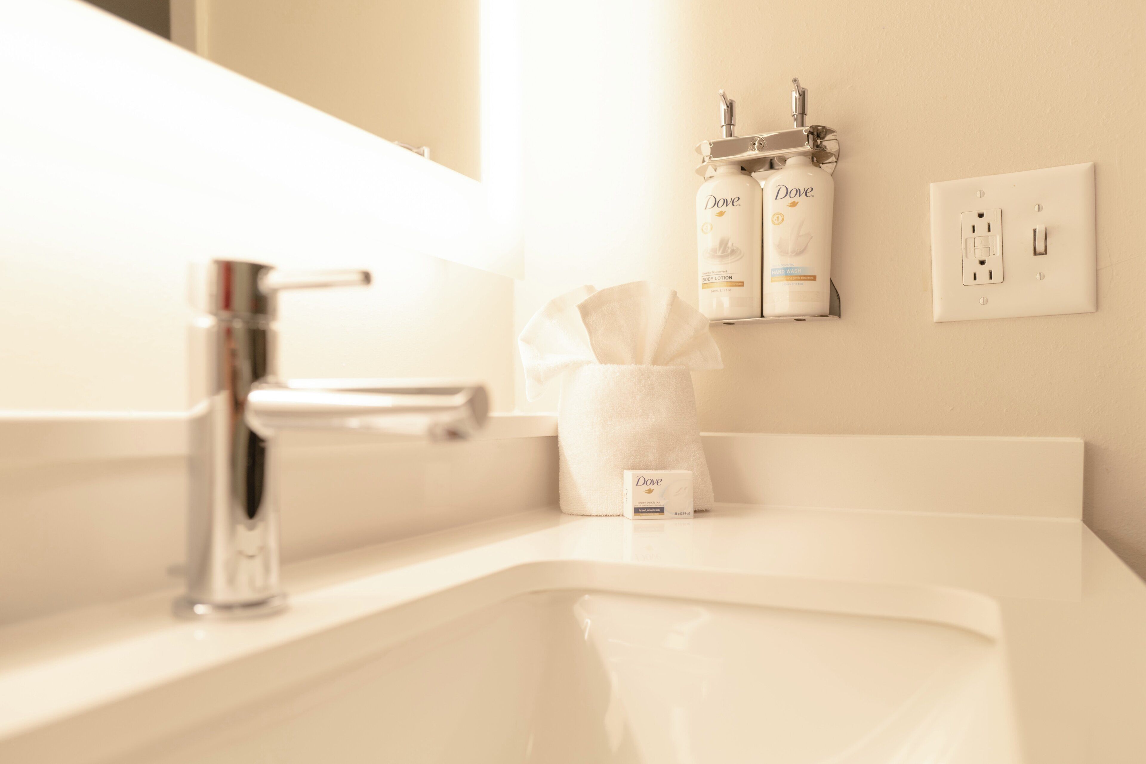 A bathroom sink with a modern faucet, a tissue dispenser, and a Dove hand wash soap.