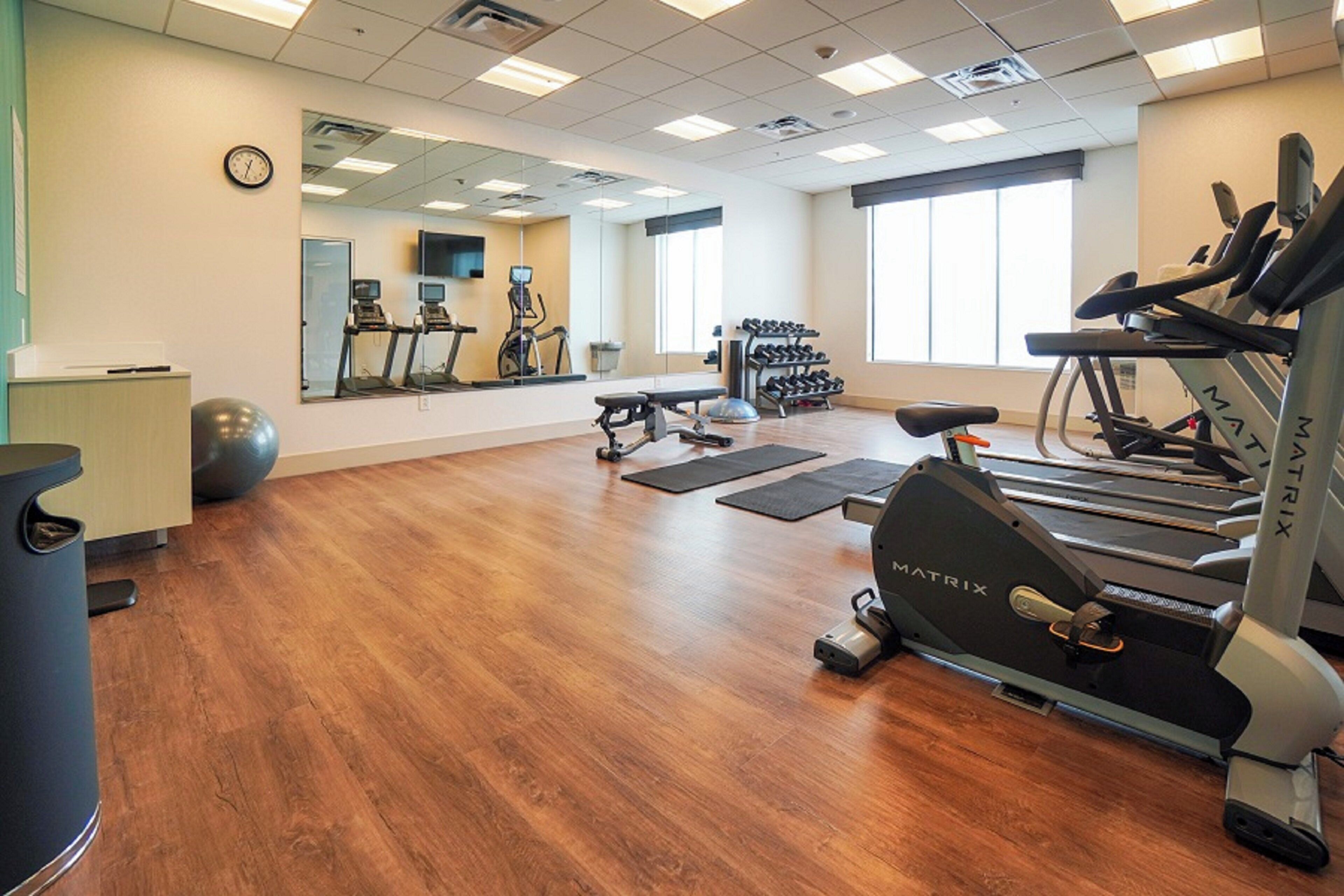 A gym with treadmills, exercise balls, and a mirrored wall.