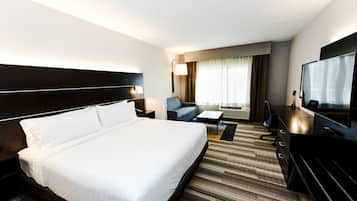 Une chambre d’hôtel dotée d’un grand lit, d’un bureau, d’une télévision et d’un coin salon avec un canapé et un fauteuil.