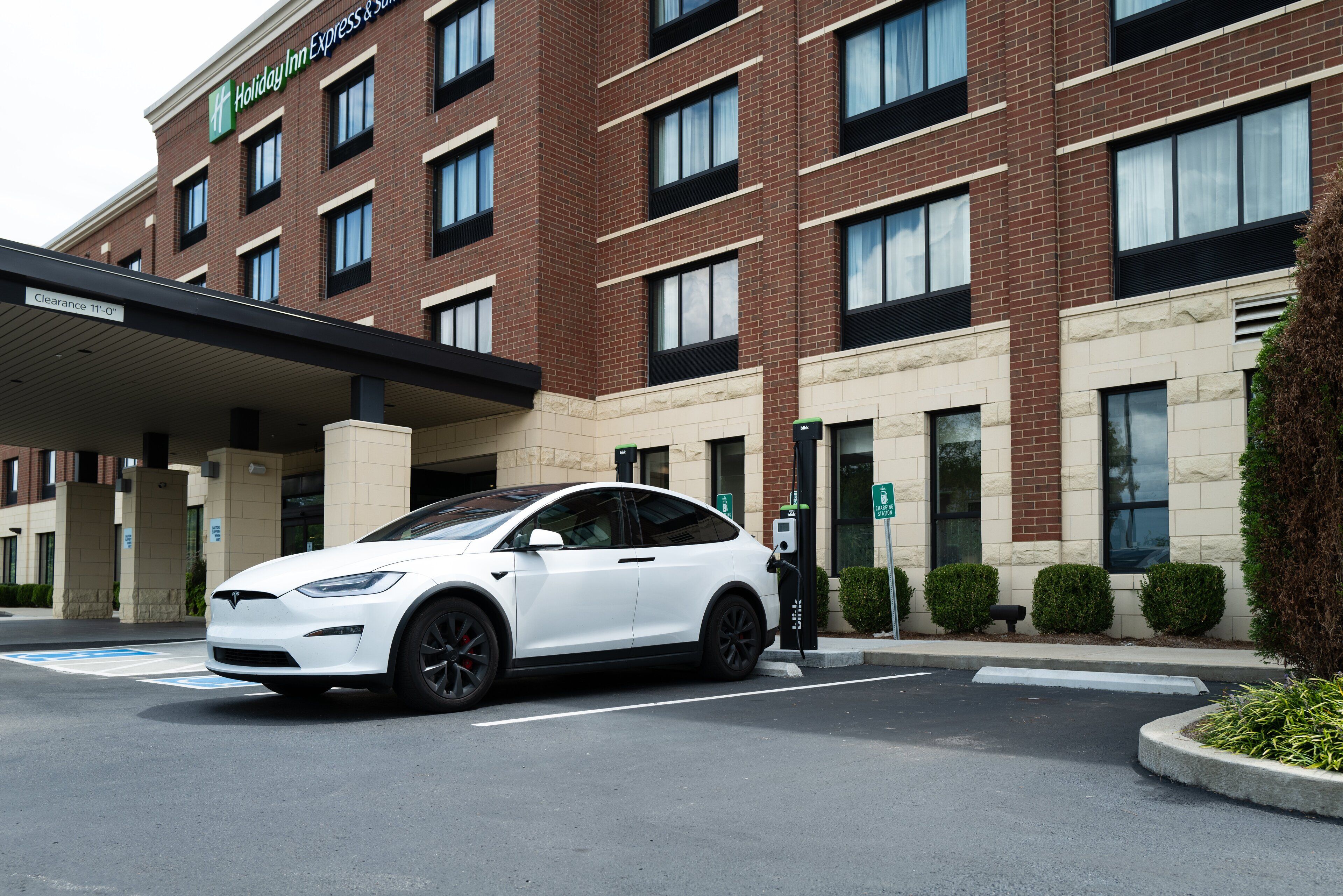 A white Tesla charging at a Holiday Inn Express & Suites hotel.