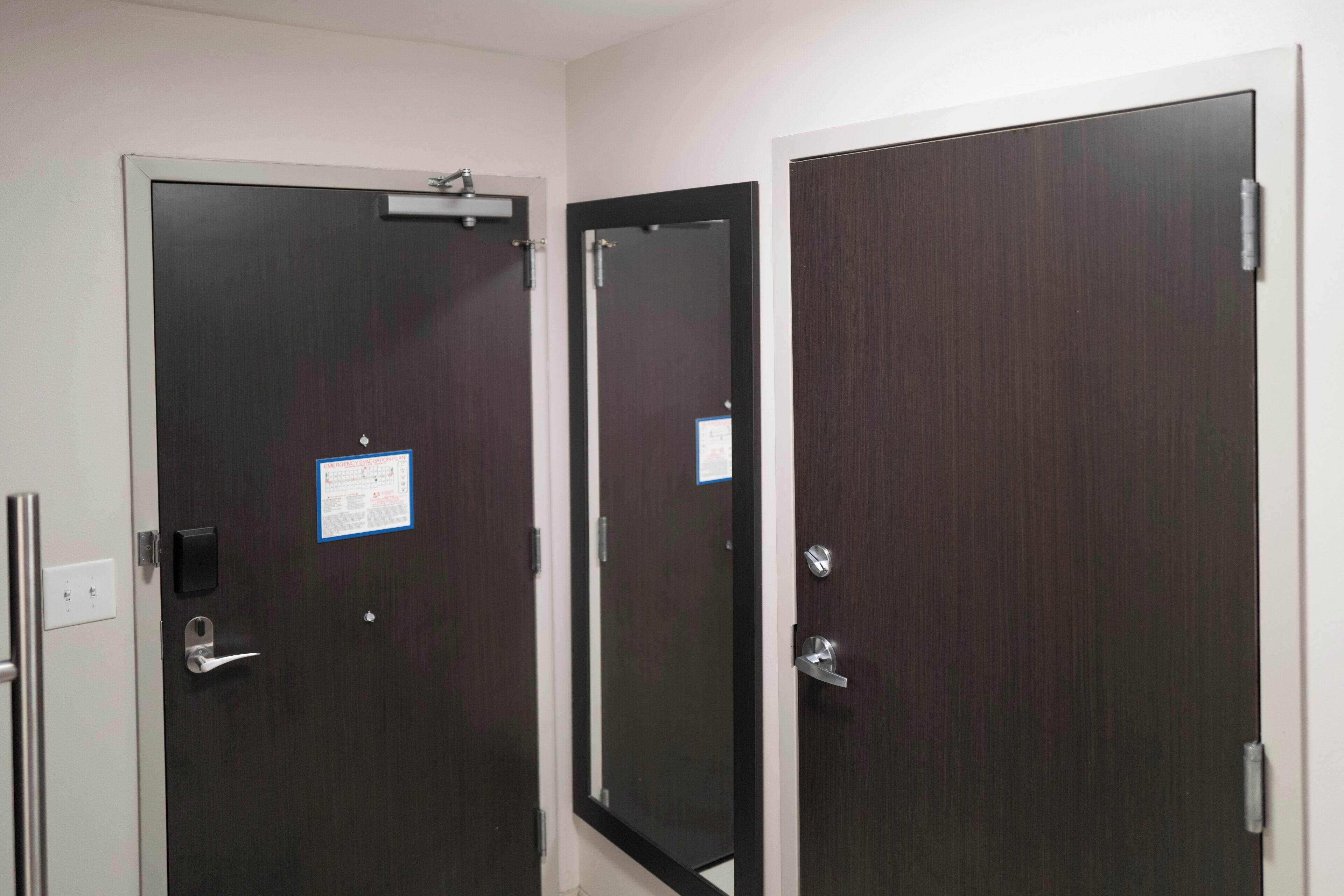 A set of dark wooden doors with a white frame, a visible emergency evacuation plan, and a door handle.