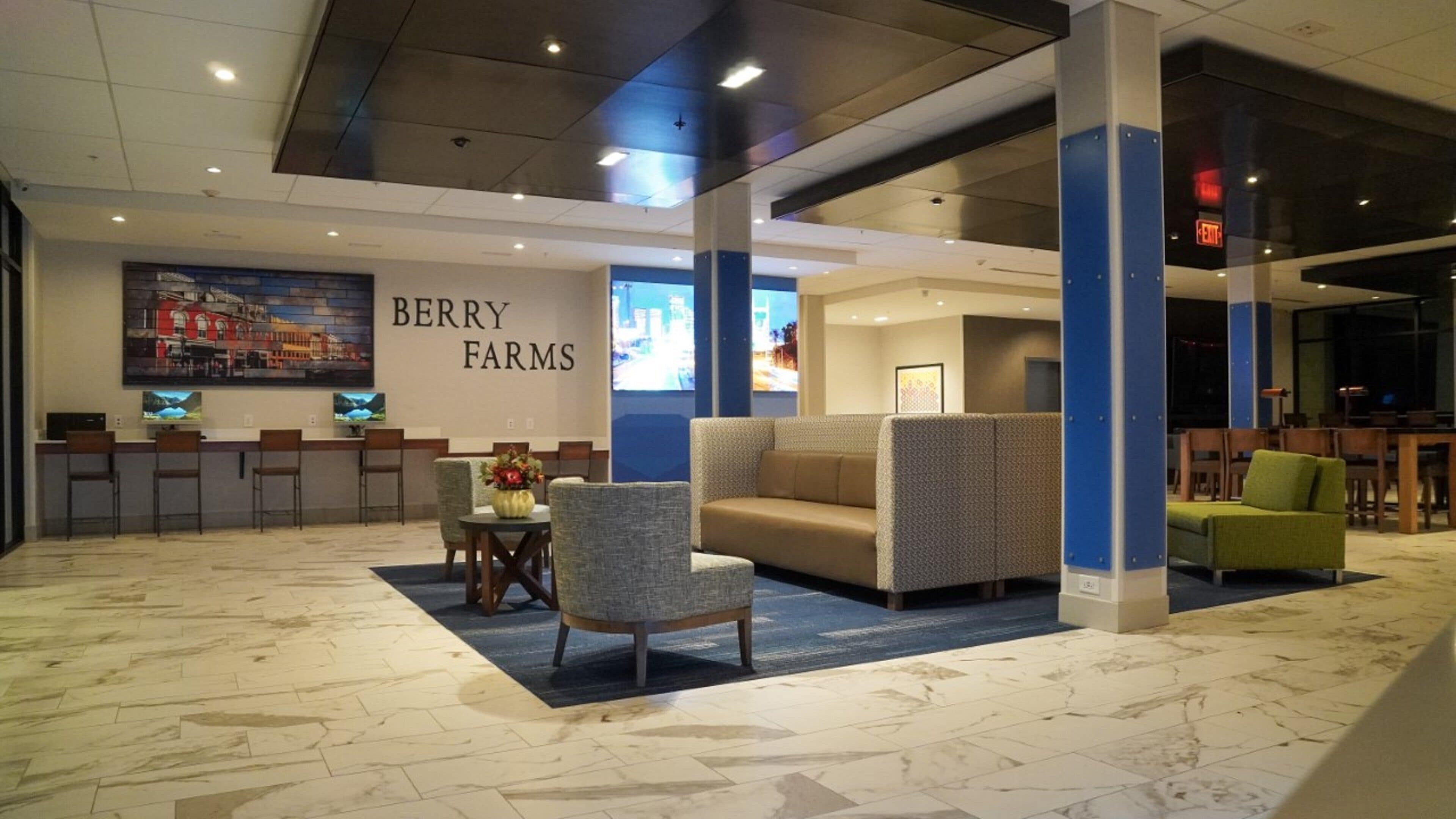 Un espace d’accueil avec des sièges, un comptoir de réception et un mur orné d’une enseigne indiquant « BERRY FARMS ».