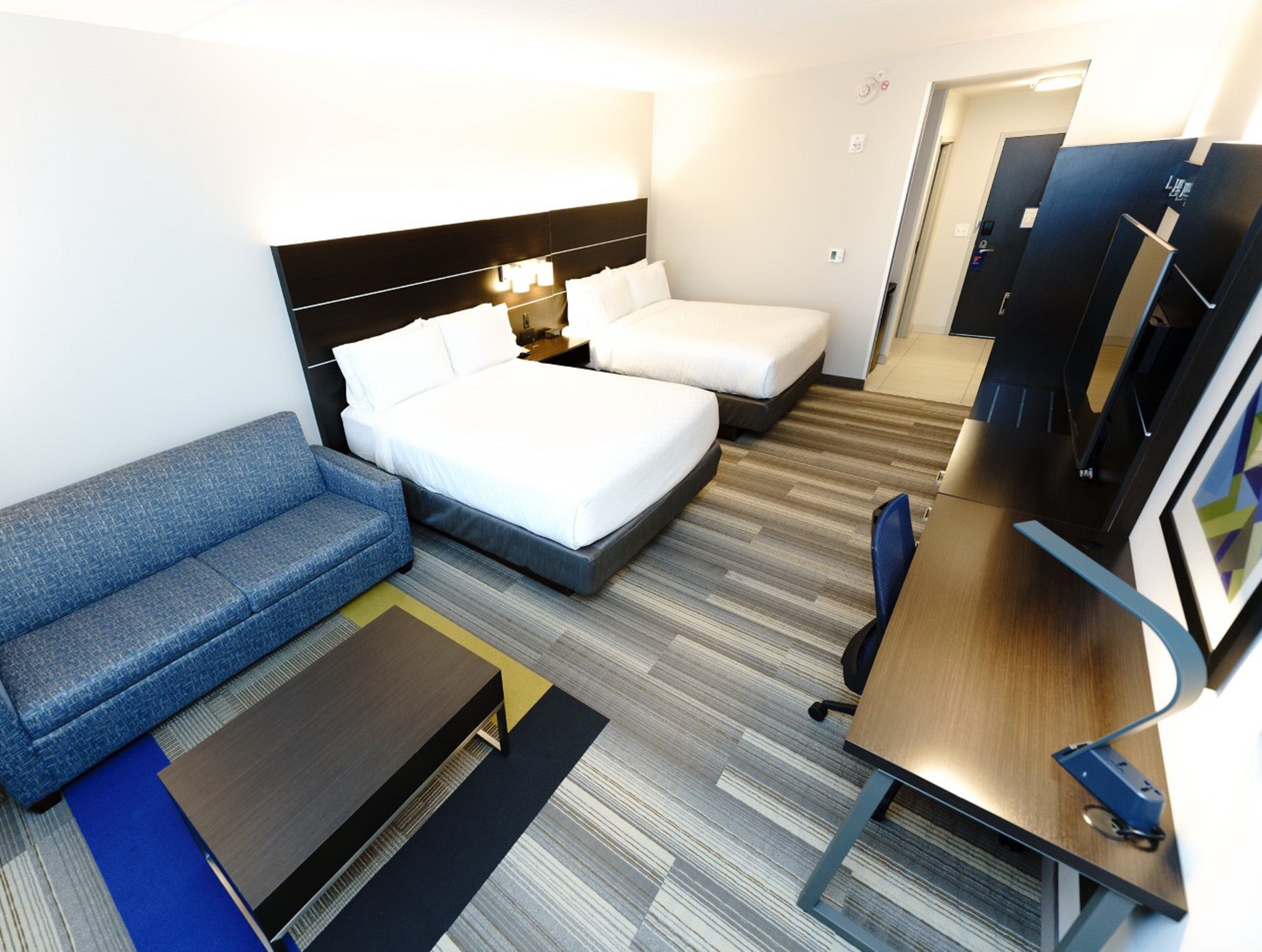 Una habitación de hotel con cama, sofá, escritorio y televisor.